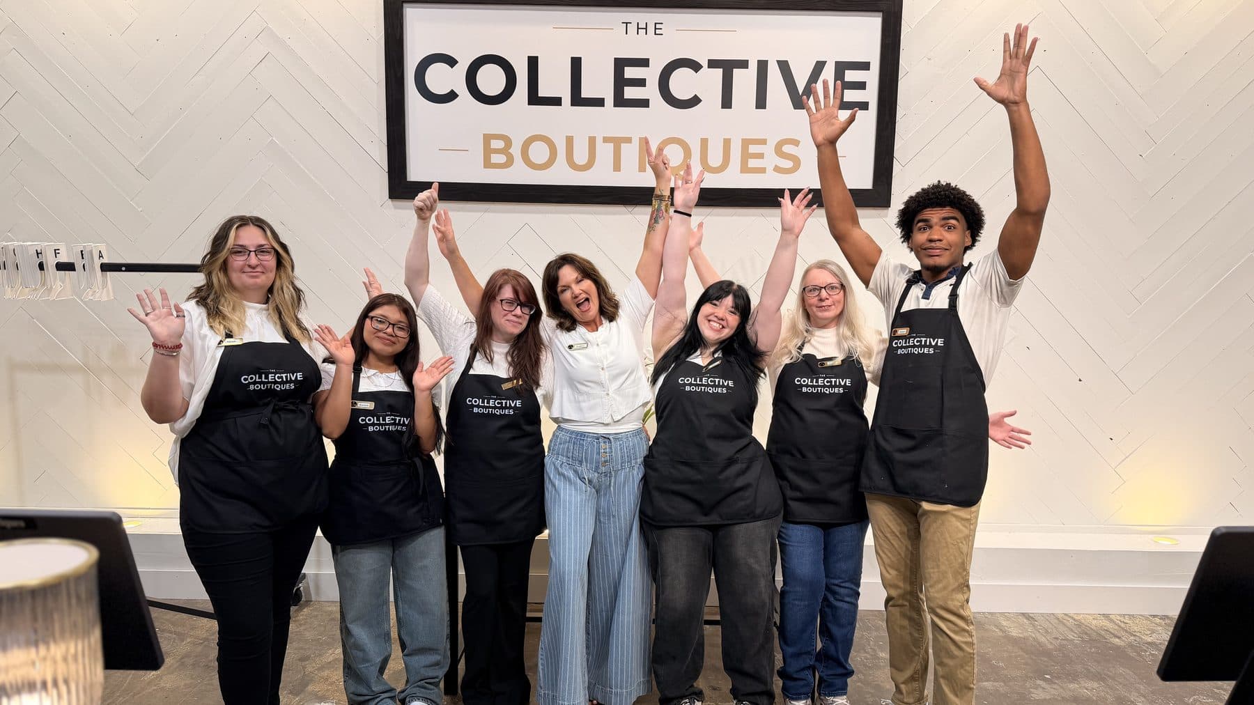 The store team at The Collective Boutiques, arms up under the store sign